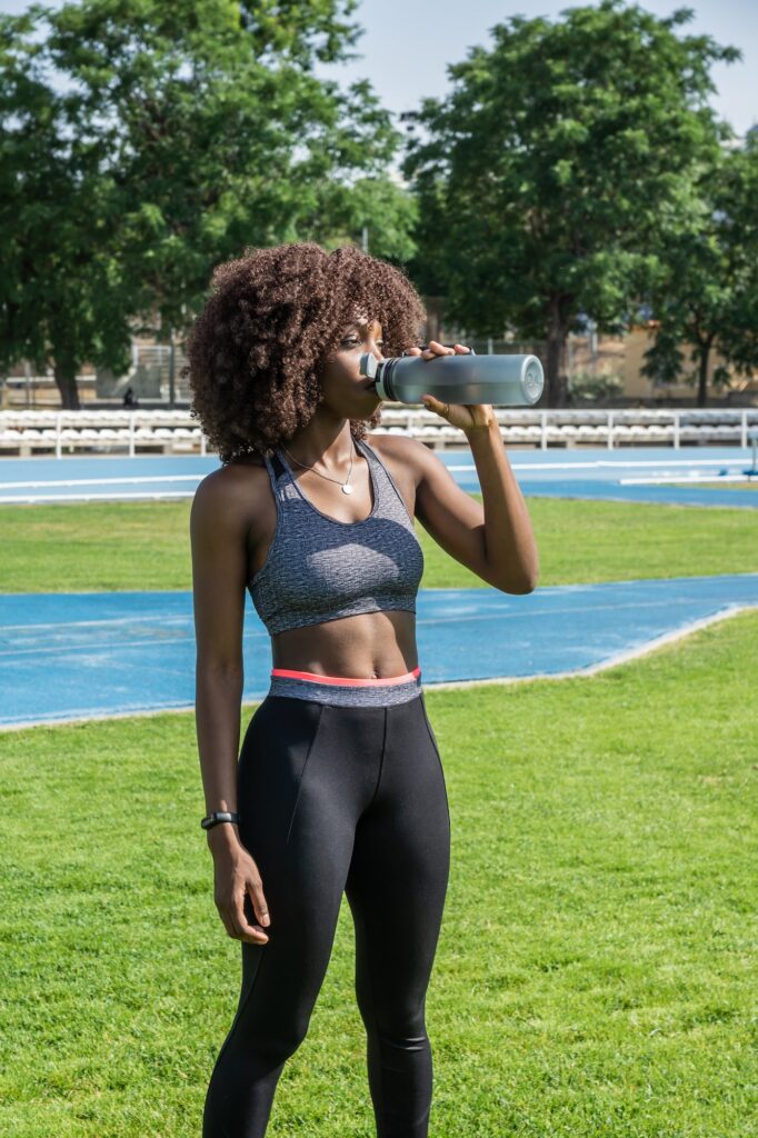 young black athlete girl with afro hair hydrating